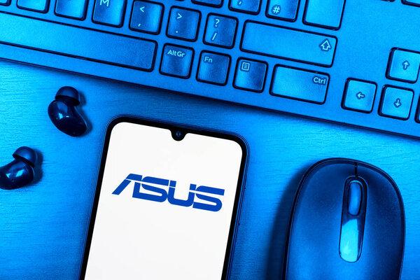 Prague, Czechia - 08 09 2025: A top-down view of a desk with a phone displaying the Asus logo. Asus is a technology company making computers and components.