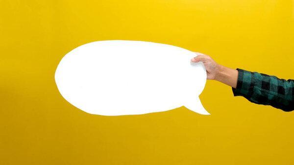 Hand Holding a White Speech Bubble with Copy Space, Isolated on a Yellow Background