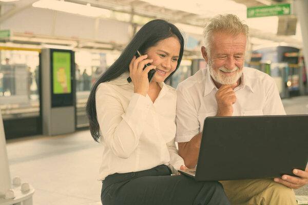 Portrait of mature multi-ethnic business couple at the skytrain station in Bangkok, Thailand