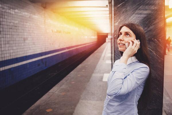 Young girl tourist talking on the phone in the subway and smiling