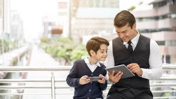 Father and son playing game smart phone together on business district urban, Dad and Son happy family concept