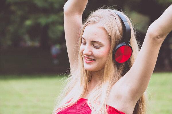 Young blonde girl smiling happy using headphones at the park.