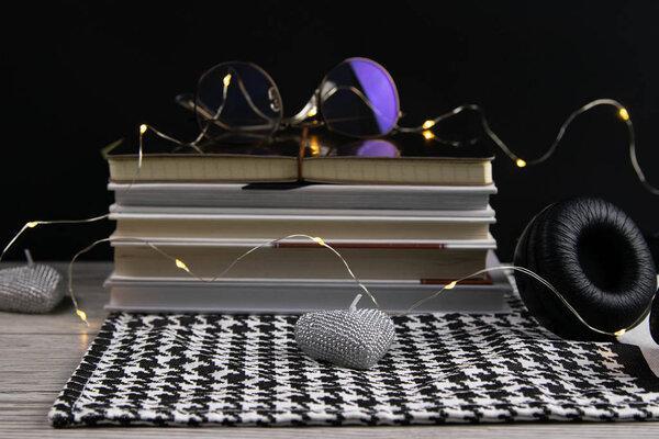 Stack of books and notepads on which are glasses and on the side of headphones