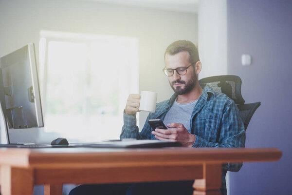 man with smart phone and cup of tea 