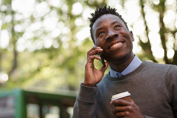 African american man talking by phone in sunny evening city