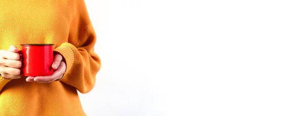 Woman in orange cozy sweater holding red cup of hot drink on white background. Copyspace, close up, mockup, banner.