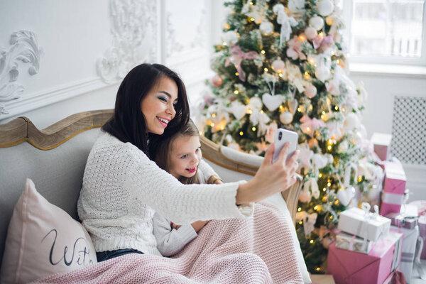 Well-groomed hand of a woman holding a phone taking a selfie with her daughter, little girl