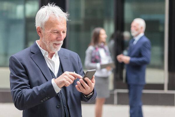 Happy senior businessman browsing internet or messaging on the smart phone