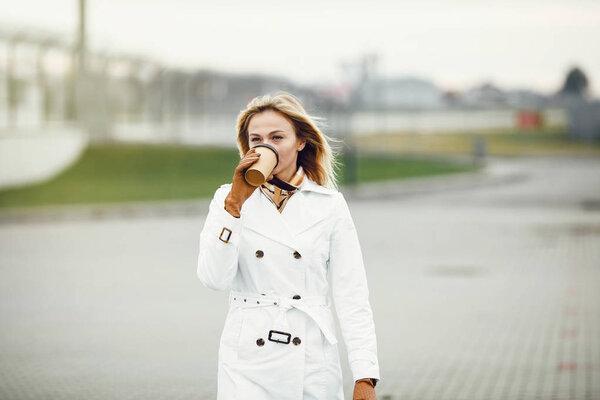 Young stylish pretty woman posing in the city streets and using 