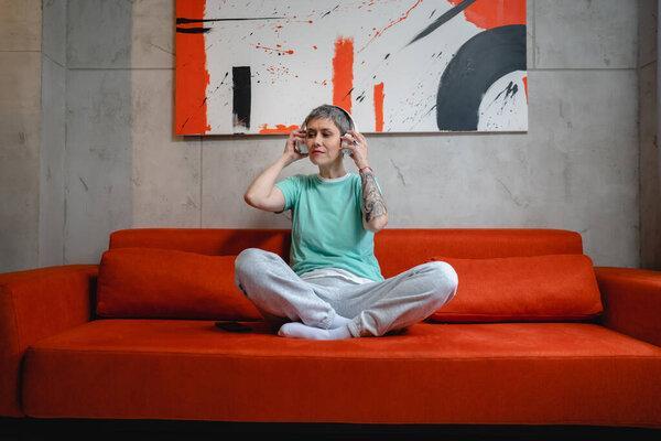 One woman sit on the floor at home with headphones use smart-phone for music listening or search for podcast online meditation or audiobook on her smarphone mobile phone online on internet copy space
