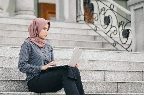 frustrated face expression, young businesswoman look at her laptop while sitting on stairs