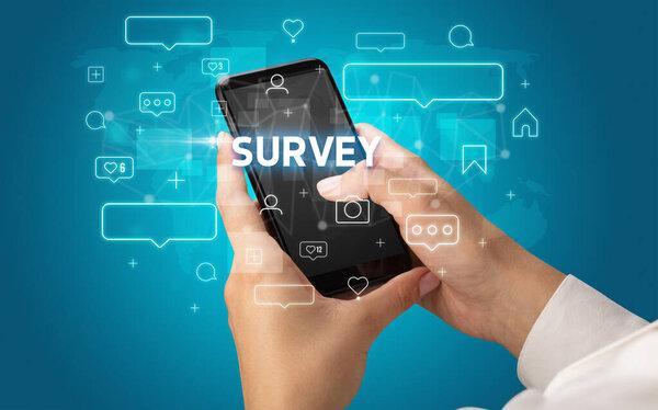 带有SURVEY题词、社交媒体概念的智能手机上的女性手打字