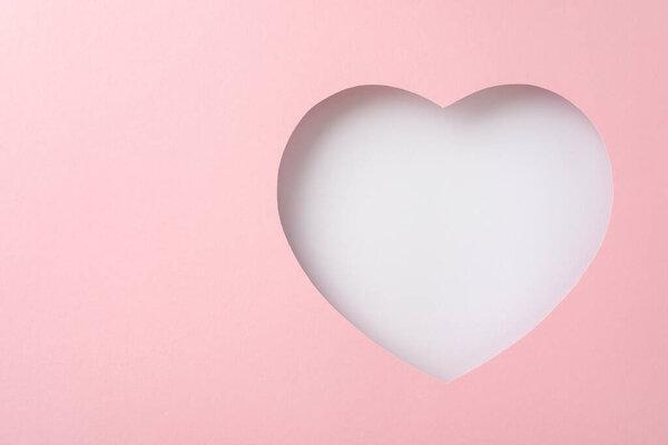 Mother's Day glamour concept. Top view image of a heart-shaped cutout on a soft pink backdrop, leaving space for personalized messages or advertising