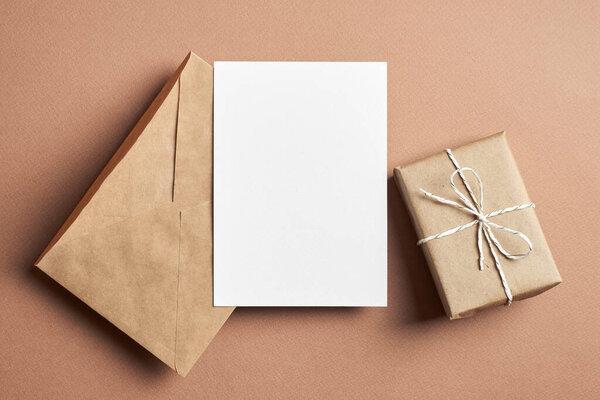 Invitation or greeting card mockup with envelope and gift box on paper background