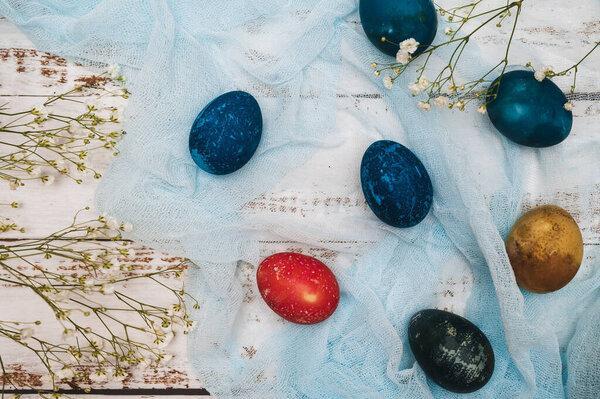 Easter eggs, small white flowers and decorations on a light background. Happy easter flat lay concept.