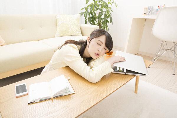 在客厅里睡笔记本电脑的年轻亚洲女人
