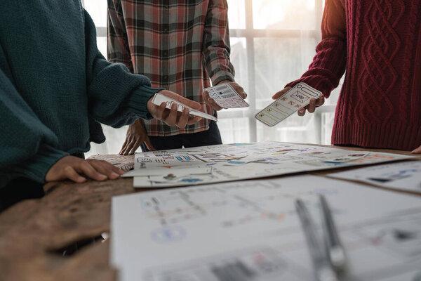 UX developer and ui designer brainstorming about mobile app interface wireframe design at modern office.
