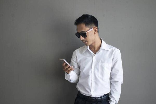 Portrait asian businese man using phone on grey background