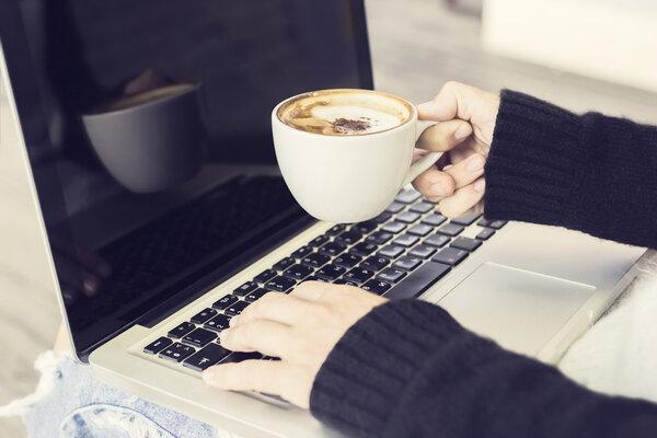 Girl with cup of cappuccino and laptop