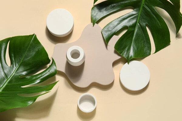 Plaster podiums and monstera leaves on beige background
