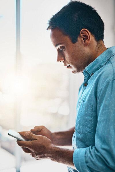 Updating his his professional work profile. a businessman using a mobile phone in an office