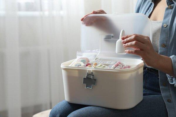 女人在室内把药品放进急救箱，特写镜头。案文的篇幅