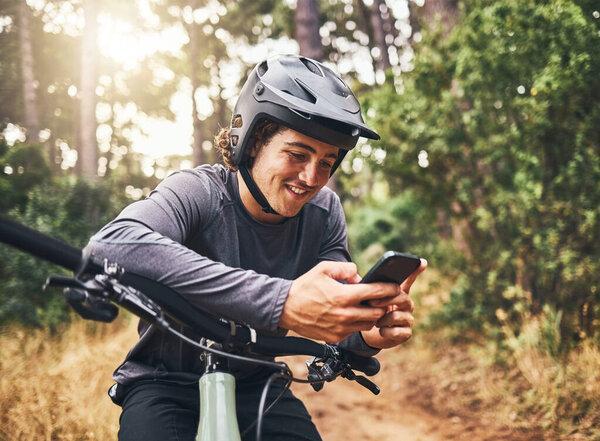 Cycling man in forest, phone gps and map direction with adventure, nature trail and bicycle break in woods. Happy mountain bike sports athlete, mobile app search and typing location guide connection.