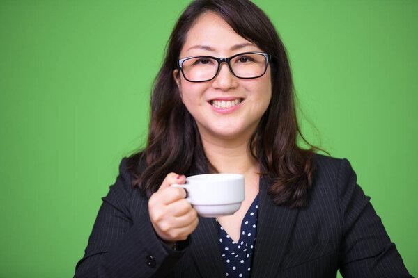 Studio shot of mature beautiful Asian businesswoman against chroma key with green background