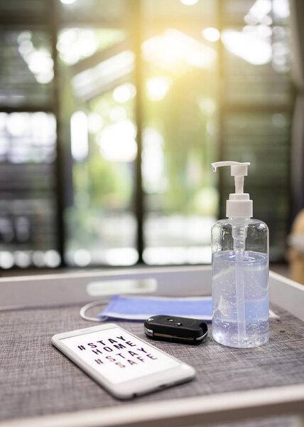 洗手凝胶瓶、车钥匙、手机和一个口罩在桌子上。