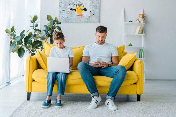 handsome father and son using gadgets at home 