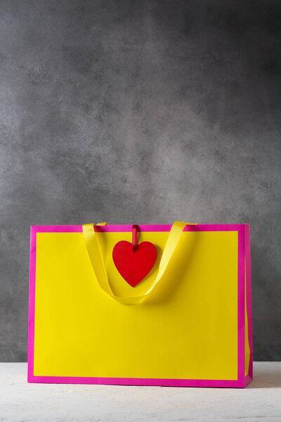 Valentines day present gift bag in bright colors pink and yellow with red heart-shaped tag, mockup