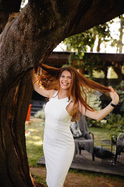 Beautiful woman in white portrait in an outdoor cafe garden in summer or early autumn with green grass and trees