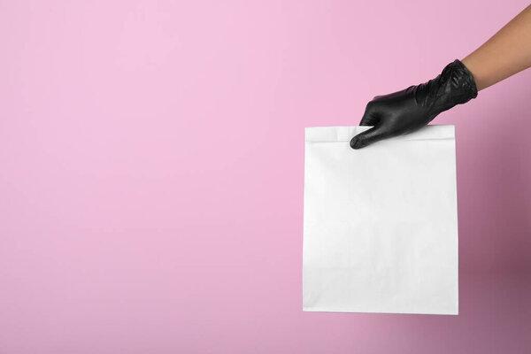 Woman holding paper bag on pink background, closeup. Space for text