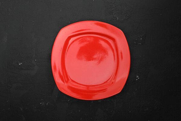 Empty Red slate plate on dark stone table. Food background for menu, recipe. Table setting. Flatlay, top view. Mockup for restaurant dish