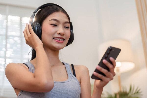 在一个舒适的空间里，女人一边听音乐，一边用智能手机与最喜欢的曲调交流，从而增强了她的放松感.
