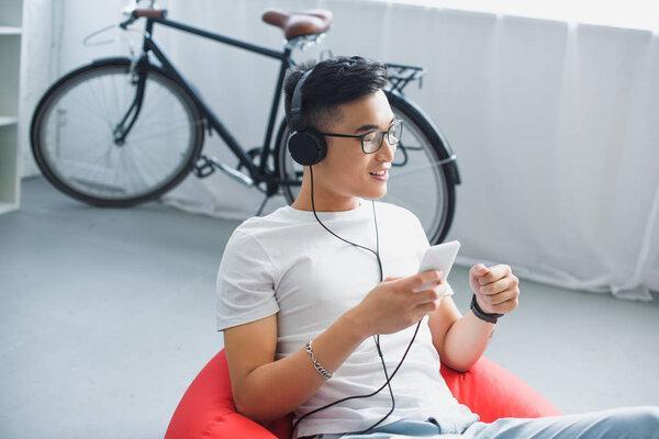 high angle view of smiling young man using smartphone and listening music in headphones 