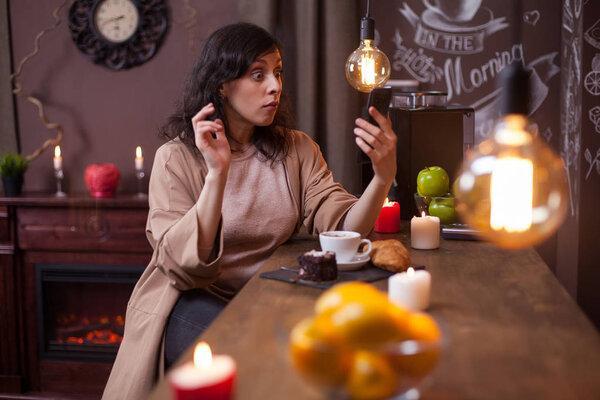 Young pretty woman using mobile phone in a coffee shop and making funny faces