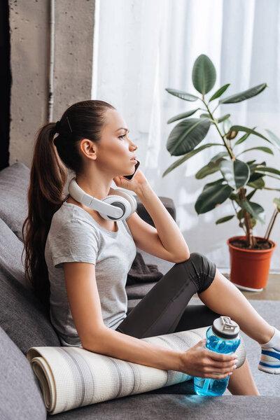 attractive sportswoman with headphones talking on smartphone at home