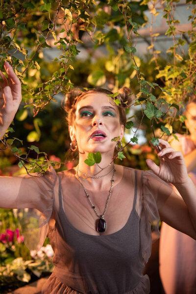 Pleasant dreamy woman standing near the tree