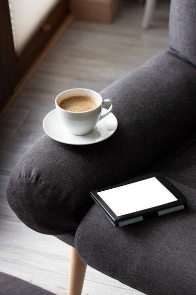 Mockup Ebook on soft modern armchair With Blank White Screen, to replace your design. Cup of Coffee for cozy atmosphere reading. Paste your book cover here