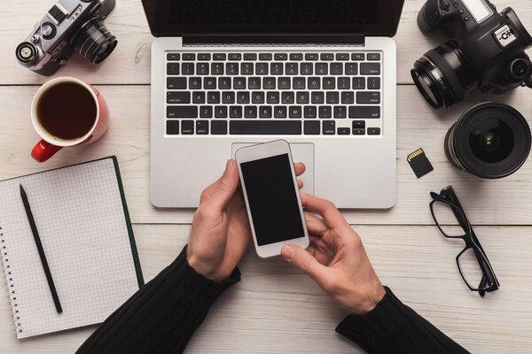 Photographer using smartphone on workplace