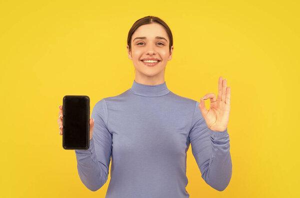 ， 幸福的女人用 ok 手势呈现智能手机屏幕，、文案空间、广告。