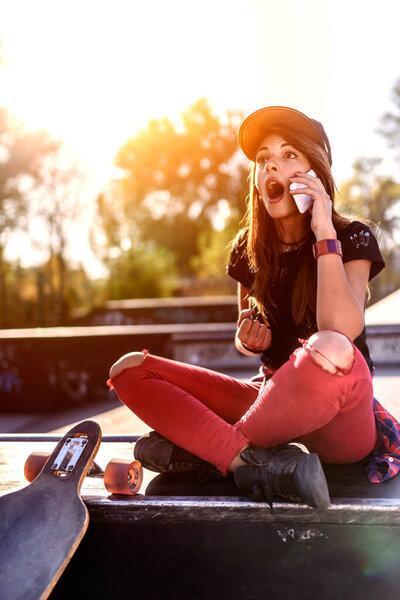pretty skater girl using phone outdoors 