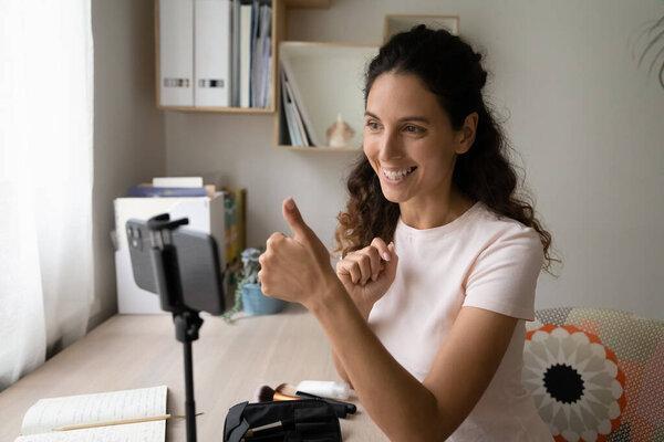 Woman record video blog on smartphone showing thumb up gesture