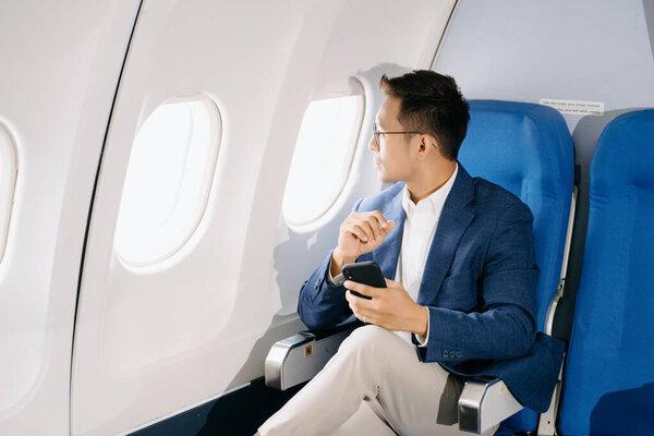 Young Asian executive excels in first class with smartphone 