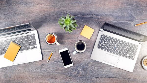 Working from home setup. Two laptopsand tea coffee mugs on wooden rustic desk. remote working or studying. Working space at home or distance learning banner or isolation lifestyle. top view