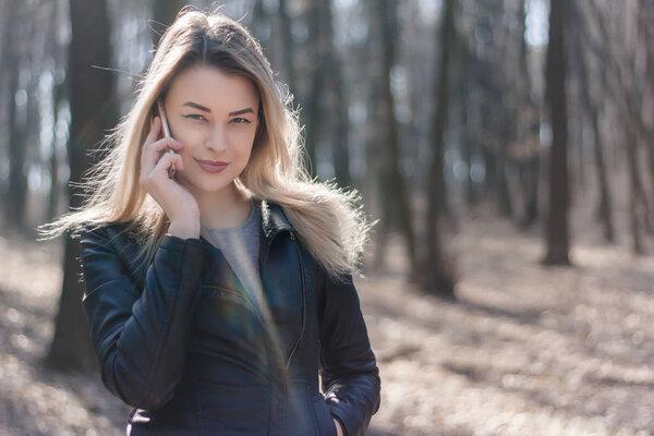 Happy beautiful woman speaking on a cellphone in the park. Autumn time.