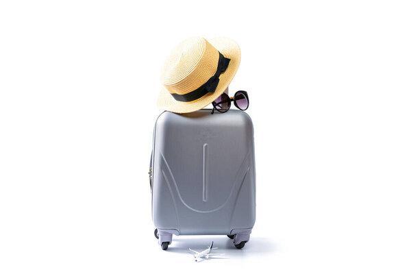 Summer concept background. Travel accessories with suitcase, straw hat, palm leaves in minimal trip vacation concept isolated on white. Copy space, summer vacation and business travel concept