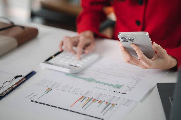 young businesswoman looking at financial information from a mobile phone, she is checking company financial documents, she is a female executive of a startup company. Concept of financial management.