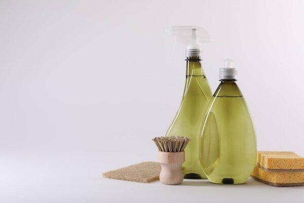 Bottles of cleaning product, brush and sponges isolated on white